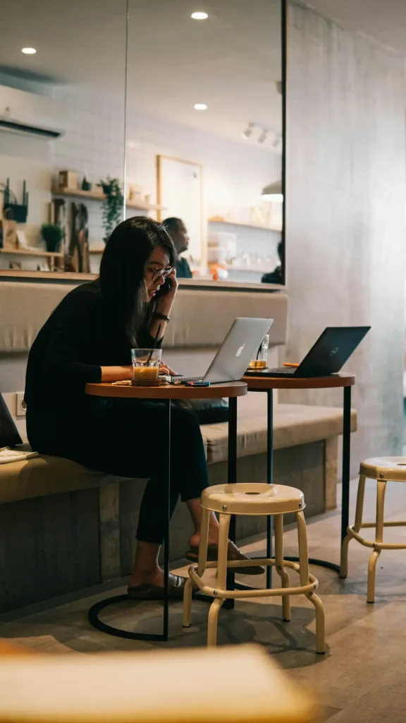 Woman sitting in a coffee shop with a laptop on the phone